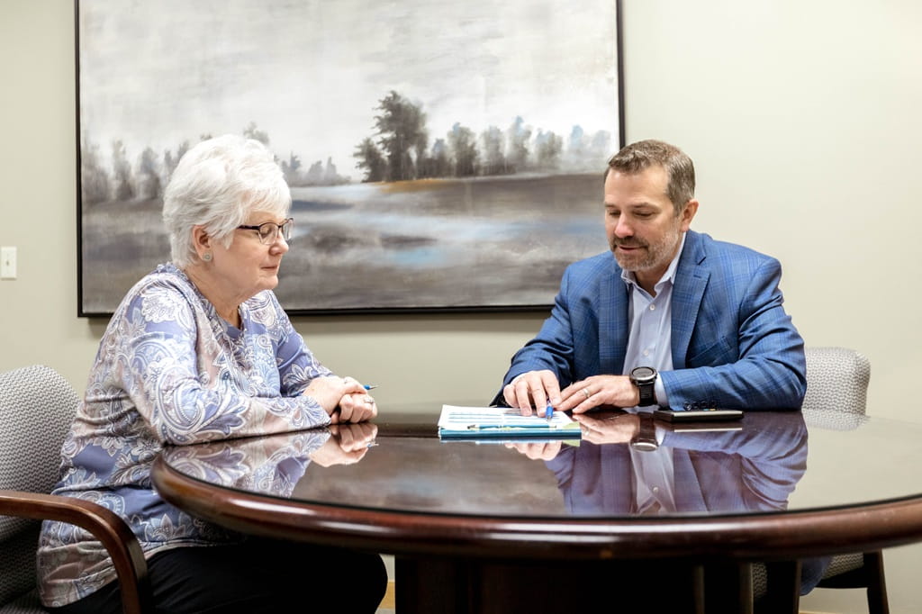 A male financial advisor goes over financial paperwork with an older female client.