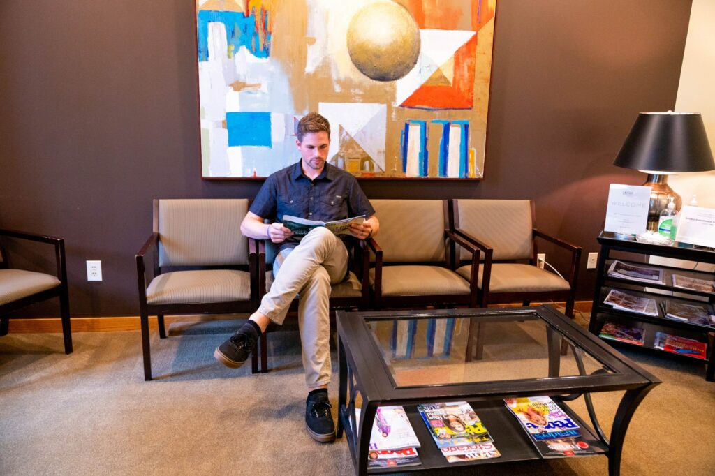 A young adult man sits in the lobby of Wiser Financial reading about how to plan for his future.