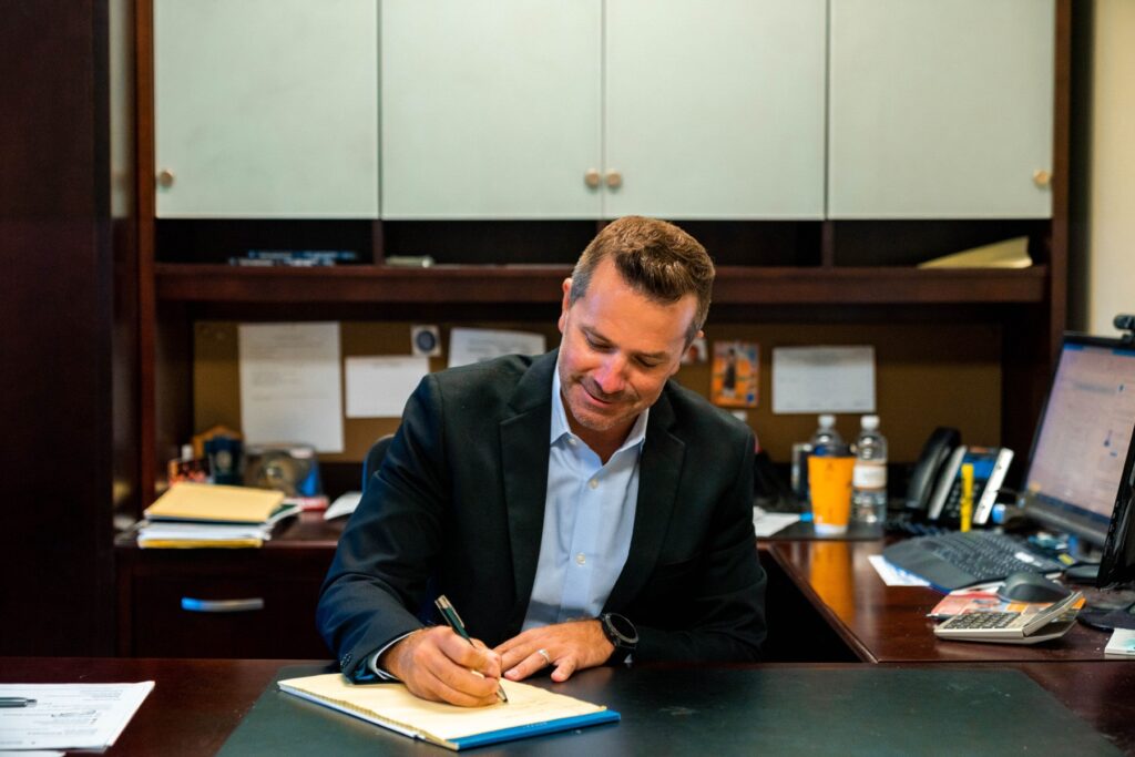 A Kalamazoo investment advisor signs papers at his desk.