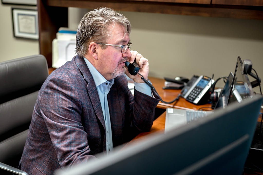 A financial advisor speaks on the phone at an office desk.