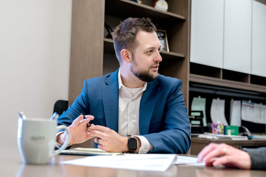 A financial advisor talks through financial planning with a client whose hand reaches through on the right side.