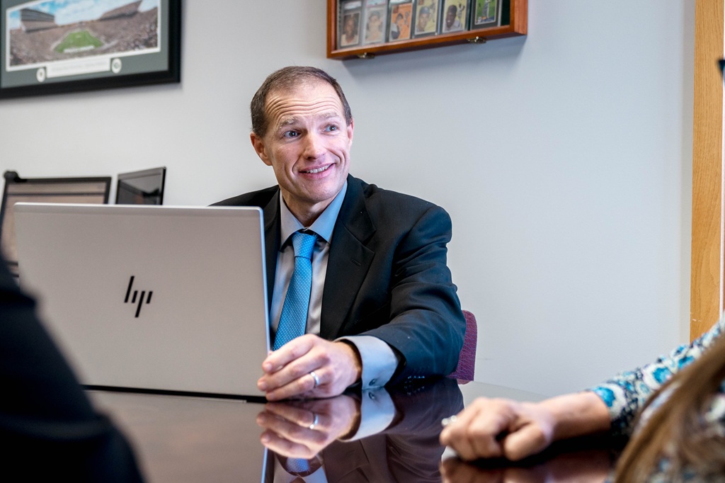 A financial advisor with an HP laptop talks to two clients whose arms are barely in frame on the left and right side.