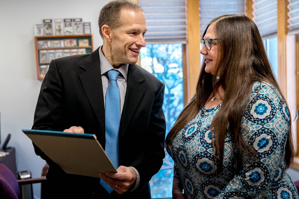 A male financial advisor smiling and explaining financials to a client.